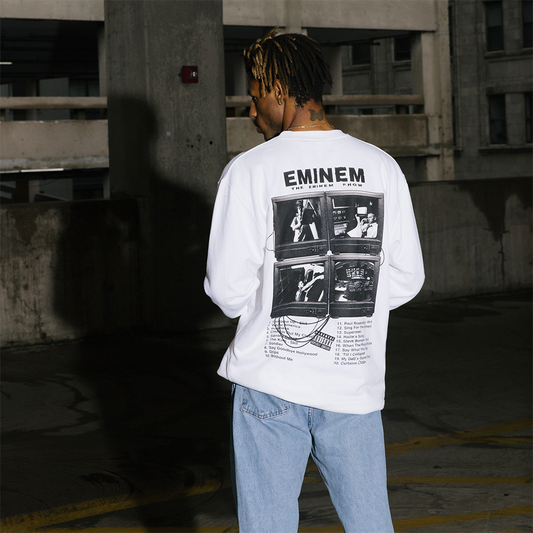 Person wearing a white sweatshirt with 'Eminem' graphic design in an urban setting